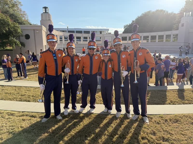 Students in marching band uniform on the field.